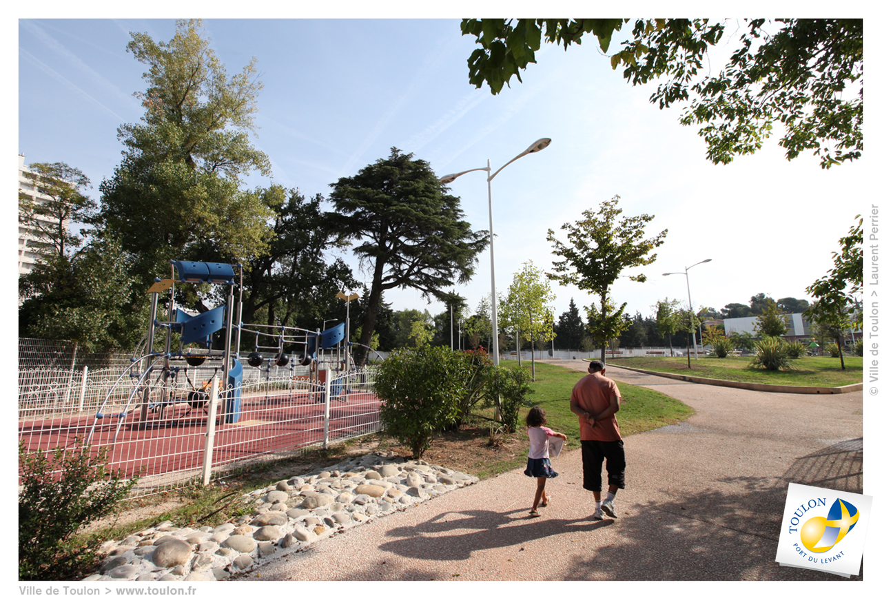 Un père et sa fille se baaldant dans le parc à côté des aires de jeux pour enfants