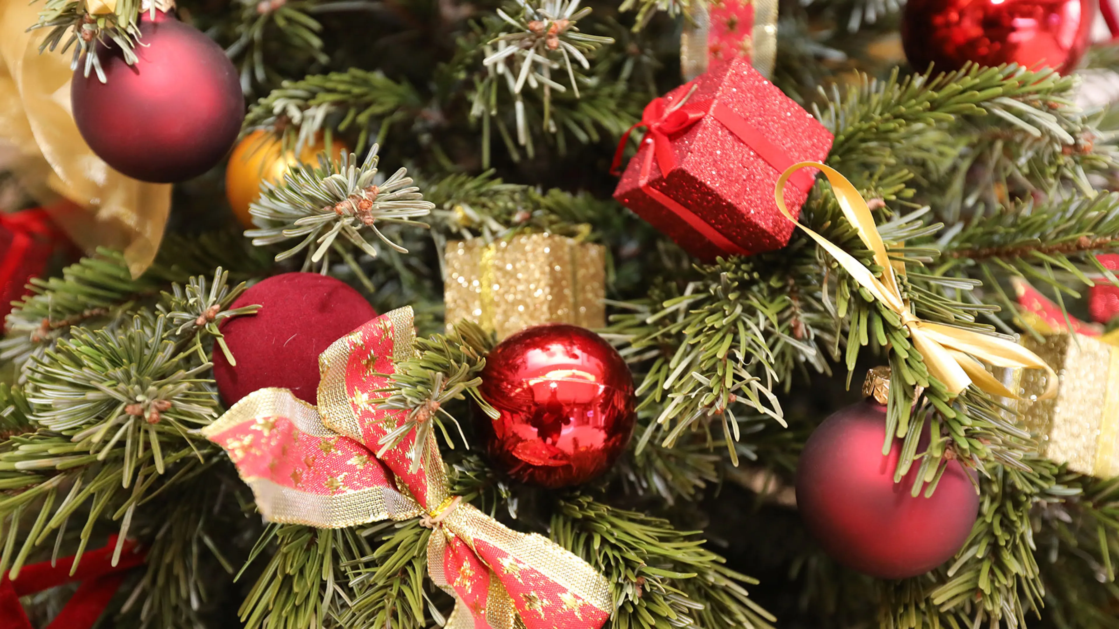 Il s'agit d'un détail d'un sapin de Noël décorés par des boules, des cadeaux et des noeuds rouge et or.