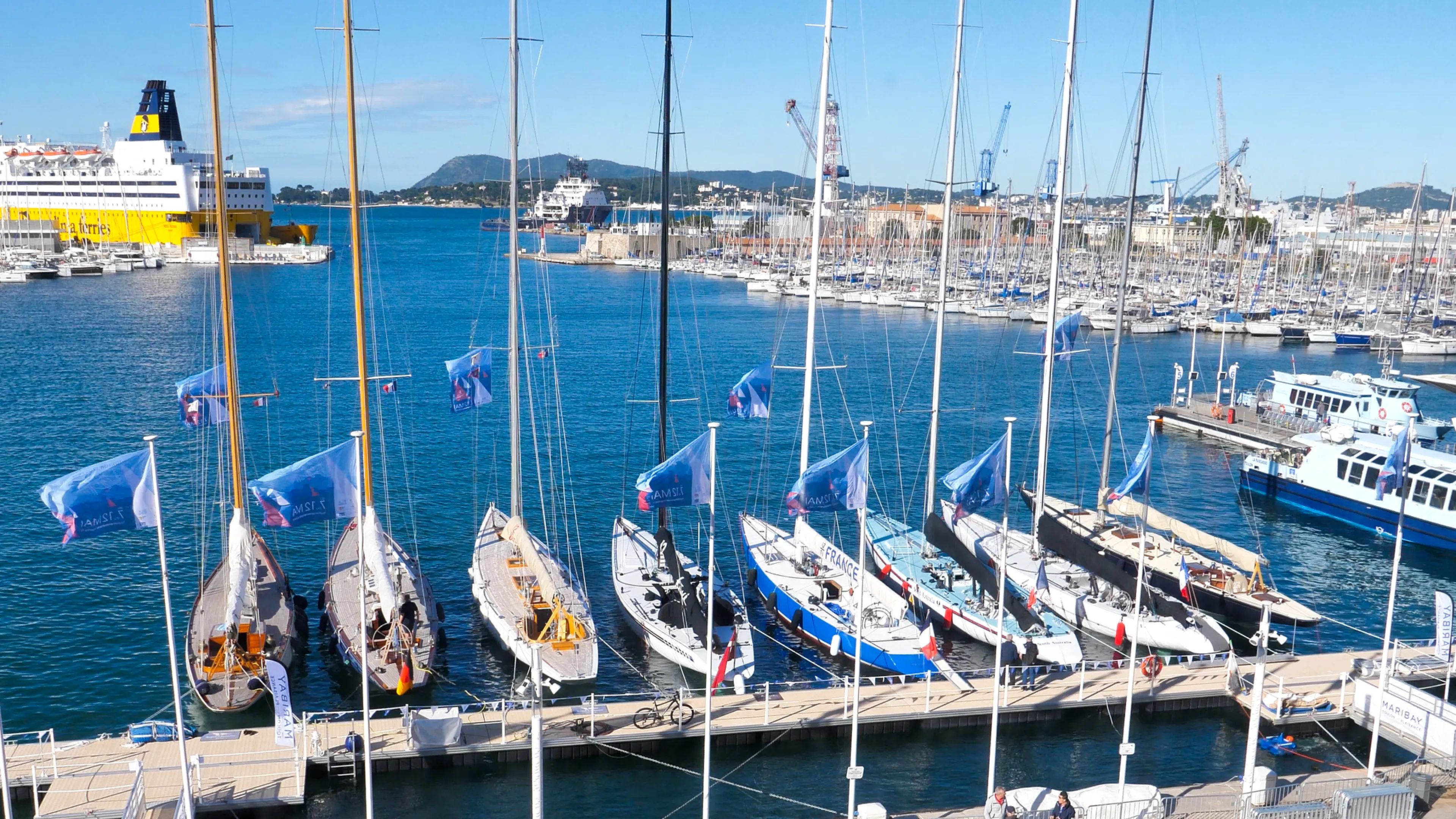 La photo montre les voiliers de type 12M JI amarrés le long du Carré du port lors de la première édition de la Toulon Provence Regatta