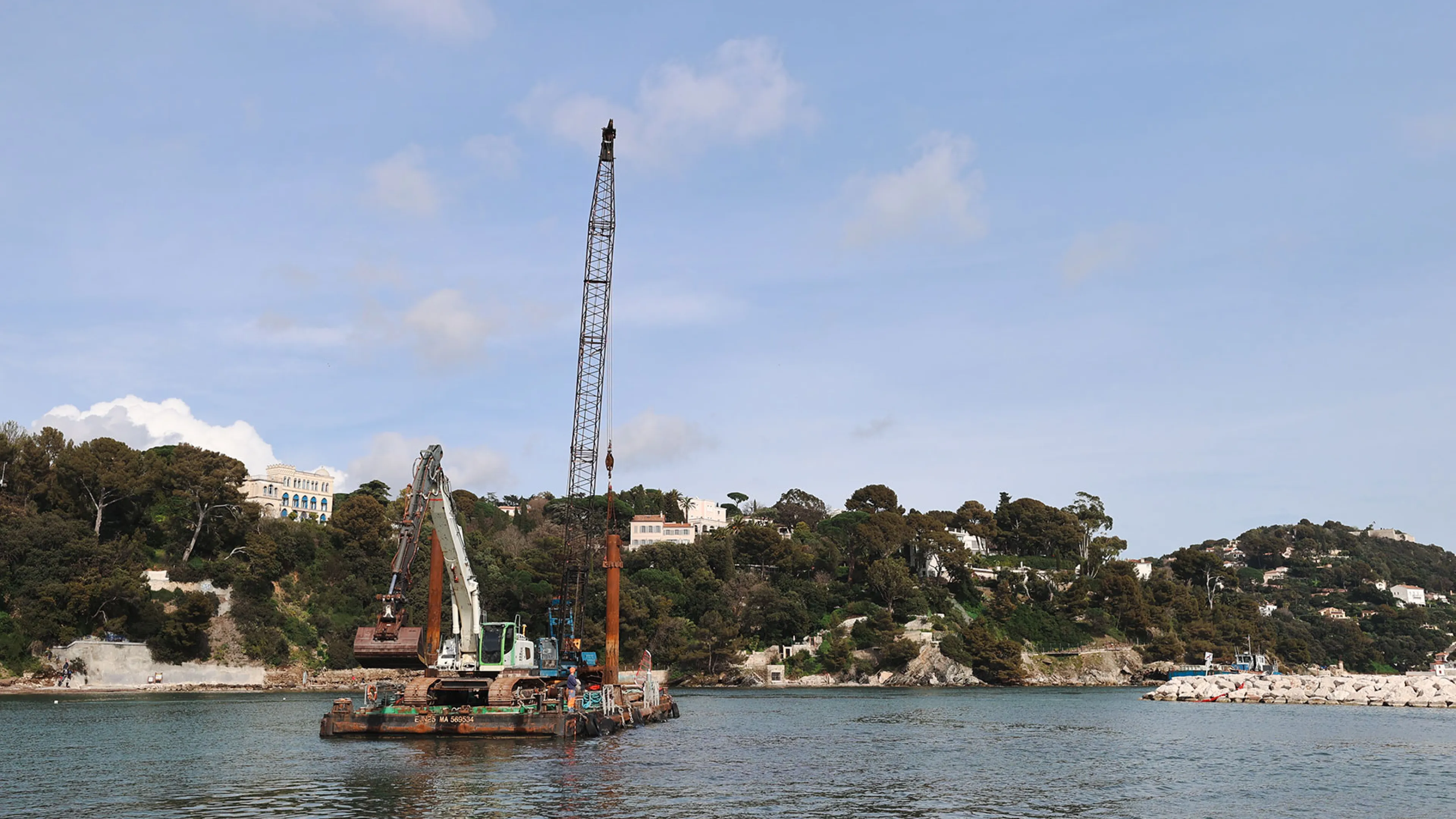 La photo montre la barge en train de draguer l'anse Tabarly.