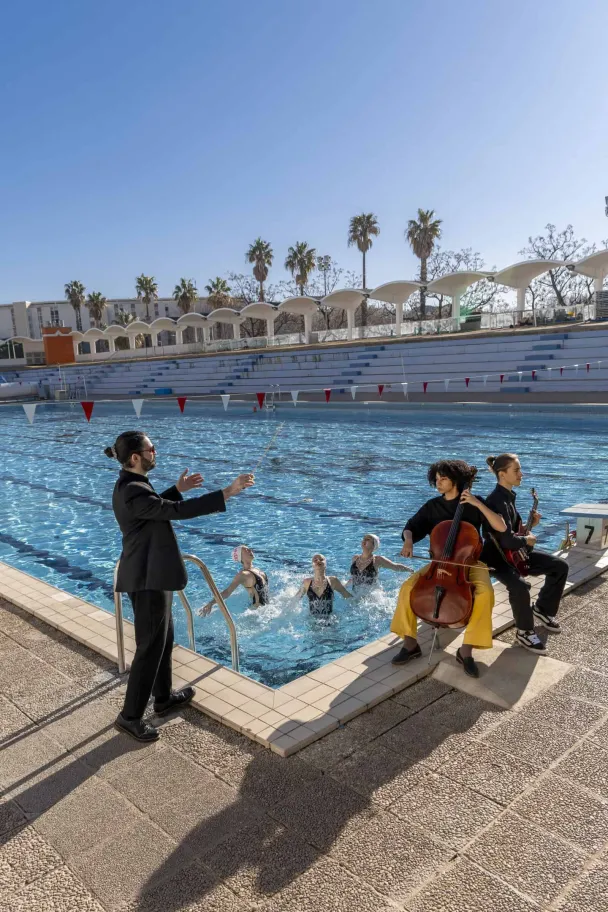 Photo d'un chef d'orchestre et de musiciens au bord d'une piscine
