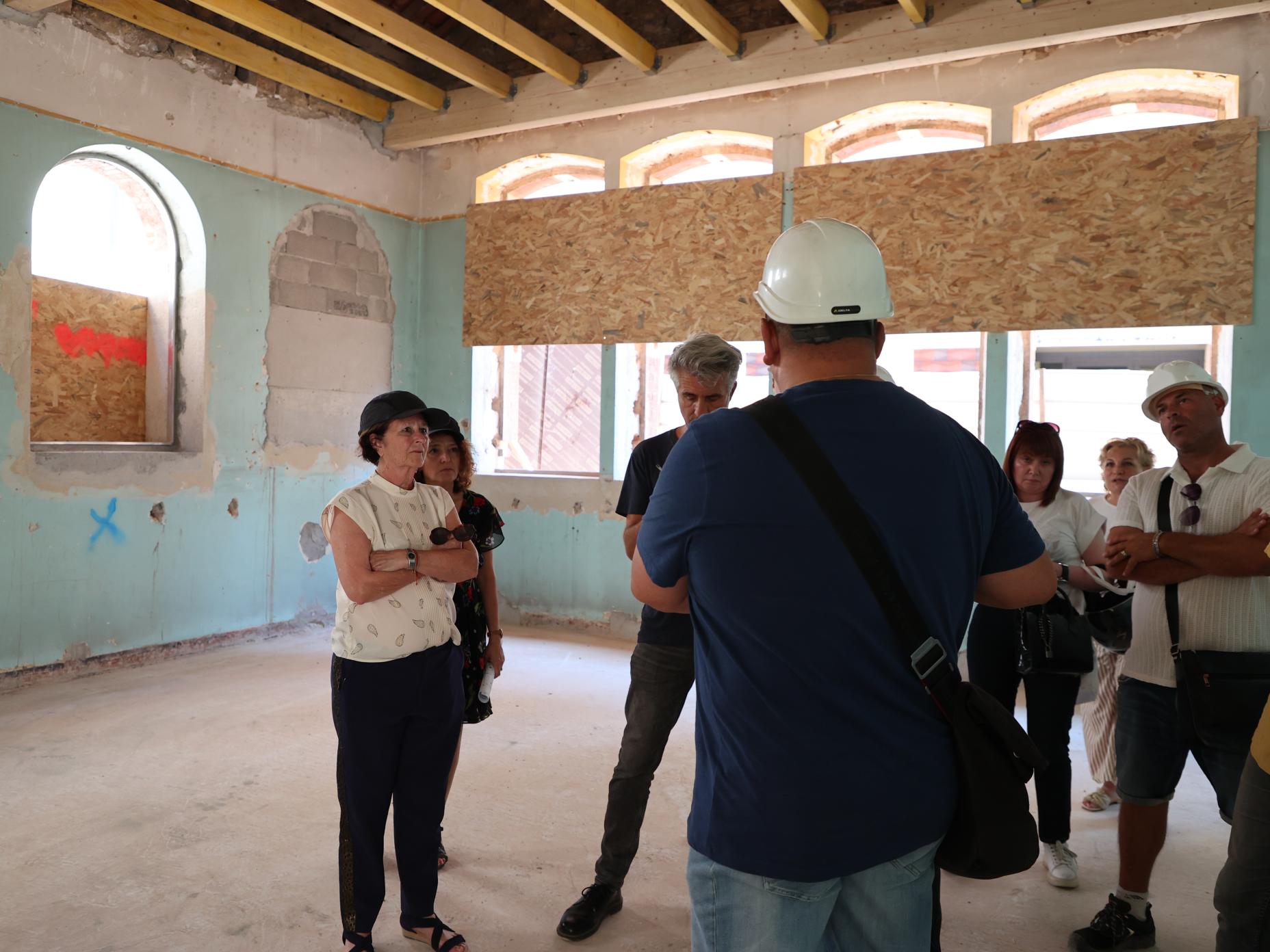 Josée Massi, maire de Toulon, portant un chemisier écru et un pantalon bleu marine écoute les explications d'Eric Boyet, en charge du chantier de la rénovation de l'école élémentaire Saint-Roch.o