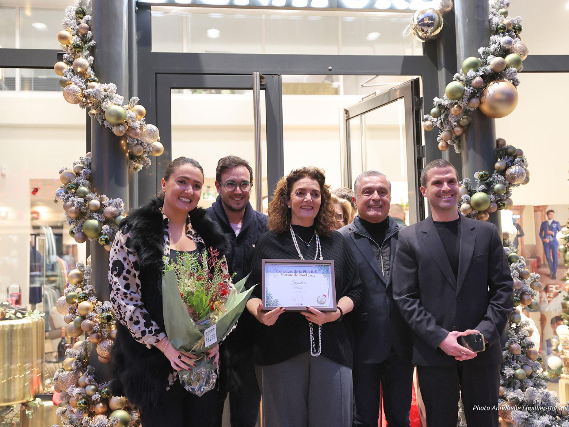 La photo montre de gauche à droite  Johanna Krespi de la boutique Signature, Boris Touaty, président des Vitrines de Toulon, Véronique Krespi propriétaire de la boutique, Thierry Campu, conseiller municipal et Christophe Moreno, adjoint au maire en charge de la dynamisation commerciale. Tous posent devant l’entrée de la boutique de robes de mariées Signature qui a remporté le concours de la plus belle vitrine de Noël.
