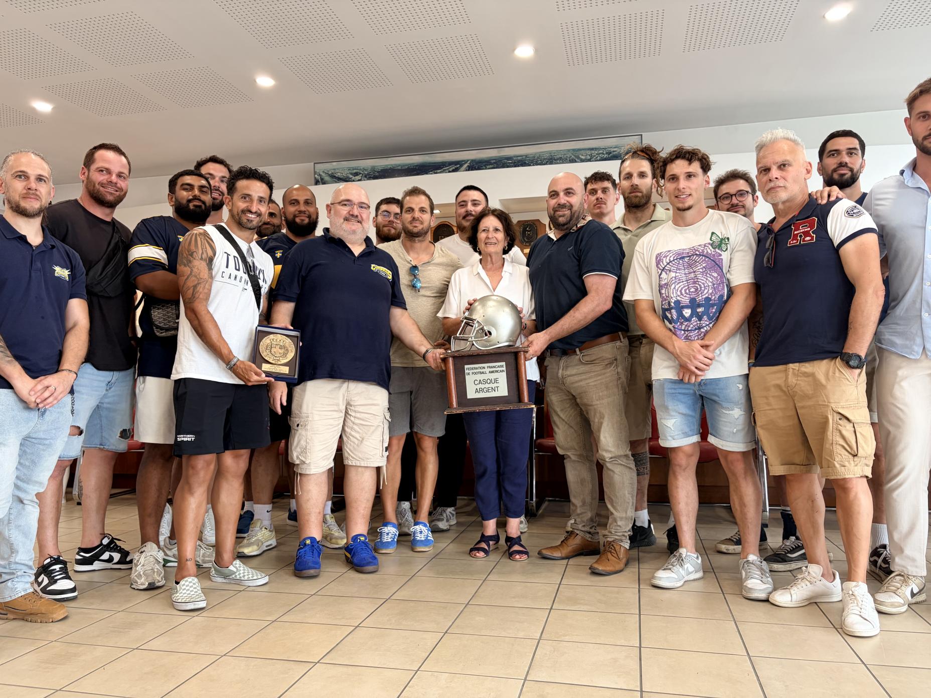 La photo montre Josée Massi entouré des joueurs des Canonniers de Toulon lors de leur réception en Mairie d'Honneur