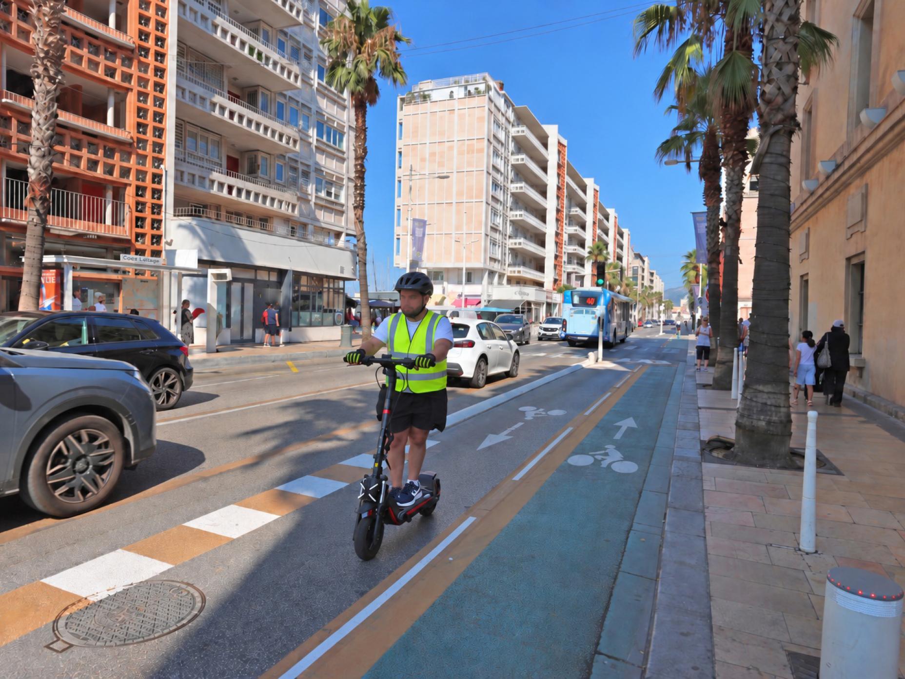 La photo montre une personne faisant de la trottinette électrique et portant les nouveaux équipements obligatoires