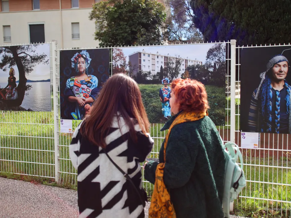 Deux femmes de dos contemplant les illustrations exposées sur un grillage