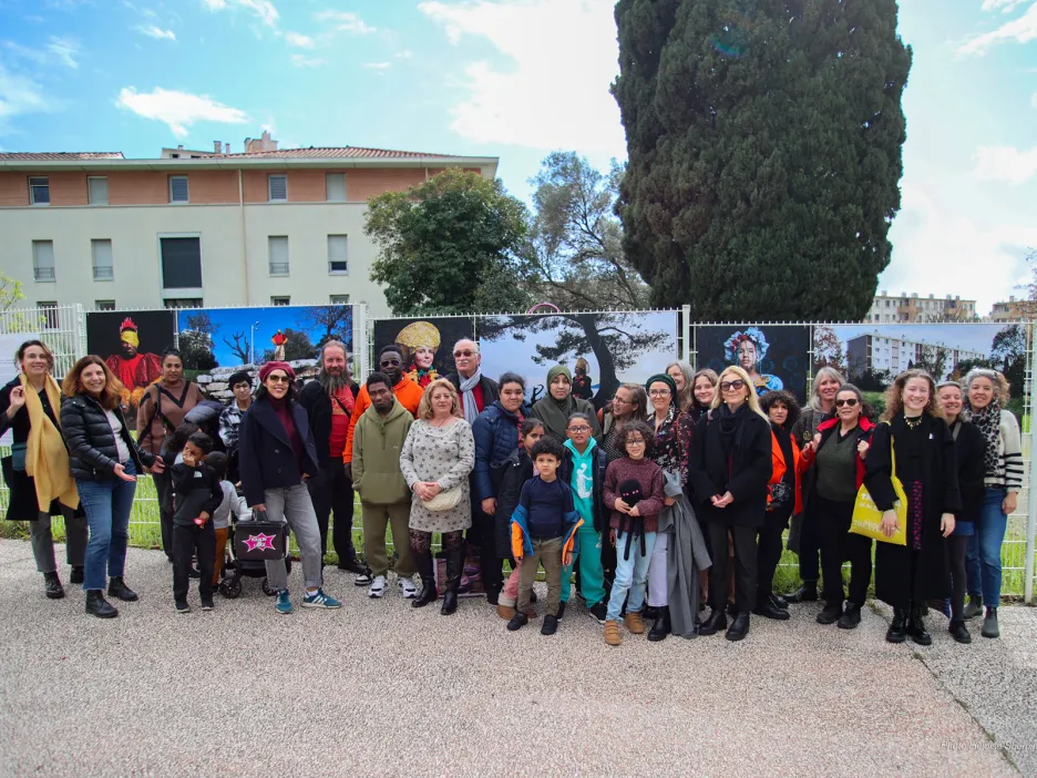 Photo de groupe des participants à l'exposition en plein air devant les illustrations des exposants