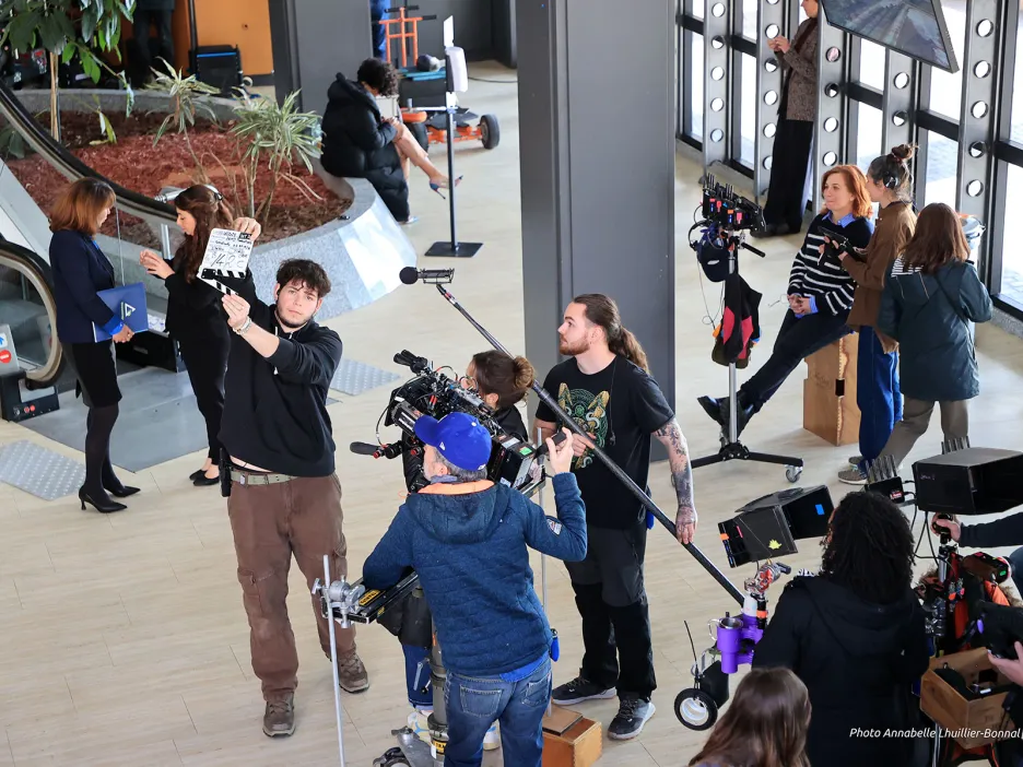Cette photo montre les coulisses d'un tournage, probablement pour un film ou une production télévisuelle, se déroulant dans le hall d'accueil du palais des Congrès Neptune.
