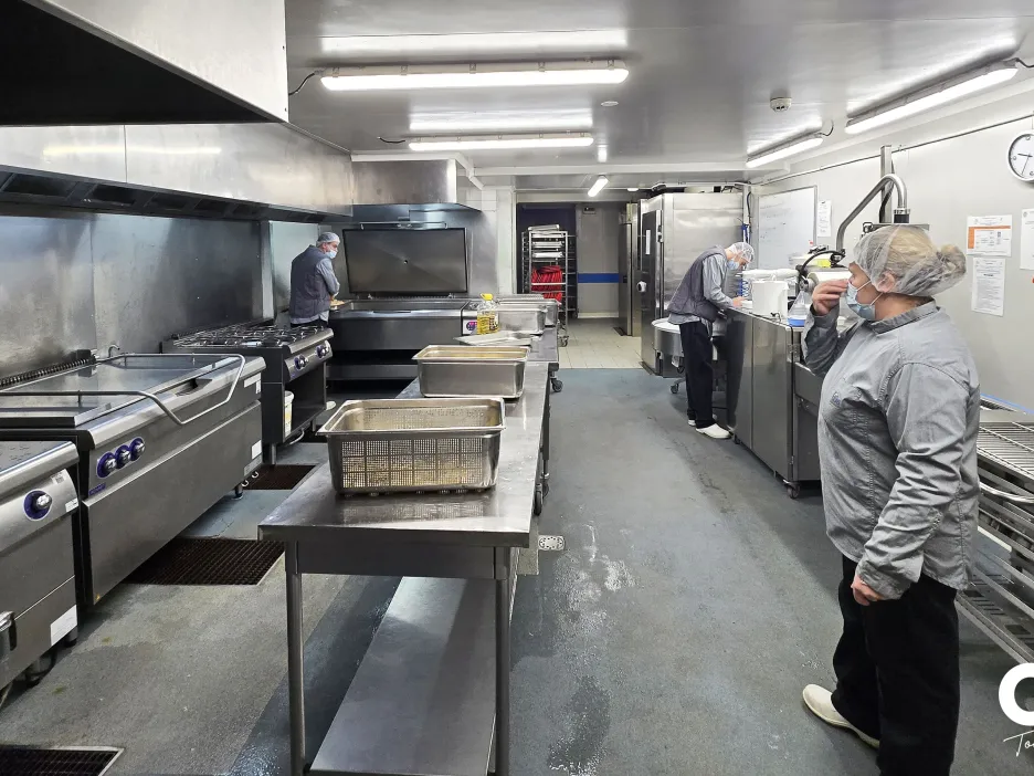 Vue d’ensemble de la zone chaude de l’UPC avec agents en activité autour des équipements de cuisson.