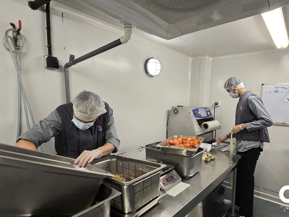 Agents de l’UPC conditionnant des préparations alimentaires sur un plan de travail inox.