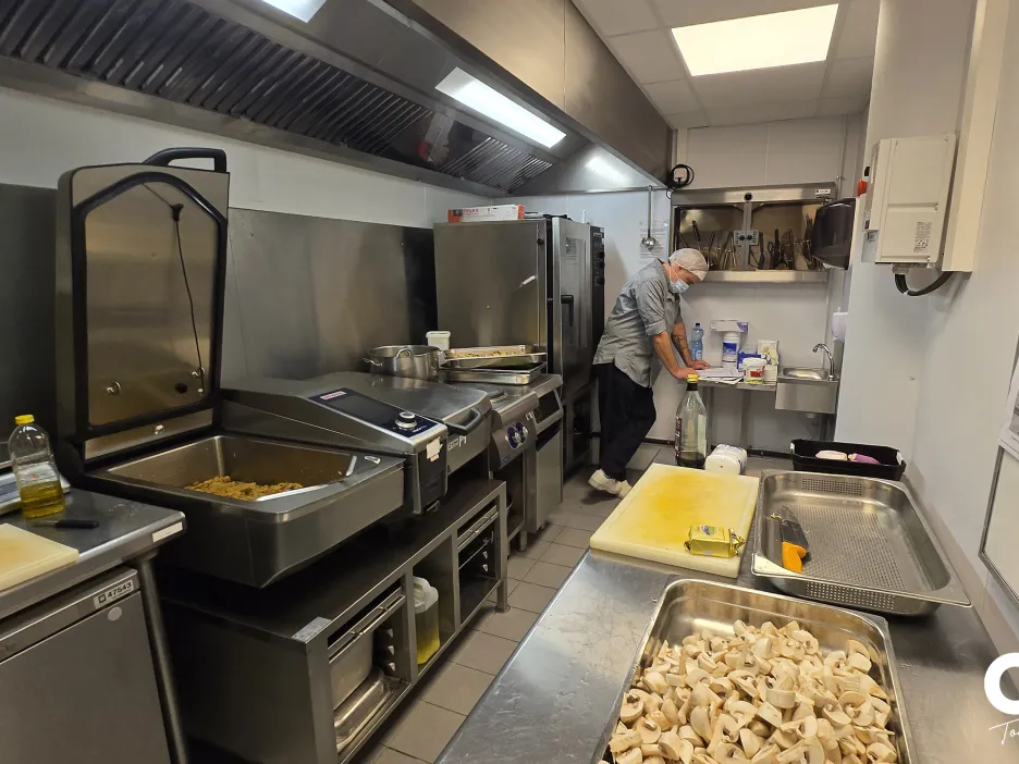 Cuisine professionnelle de l’UPC avec équipements inox et préparation des repas en cours.